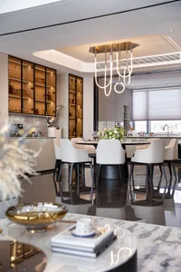 A modern kitchen with marble countertops and a dining area with white chairs and a round table.
