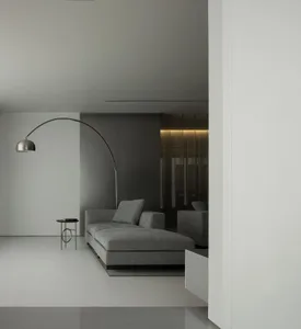 Modern living room featuring minimalist gray furnishings and a sleek, arching floor lamp.