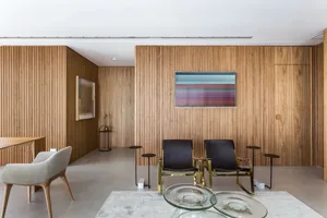 A modern living room featuring a wooden wall, glass coffee tables, and contemporary furniture.