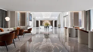A modern hotel lobby with marble floors and white and brown furniture.