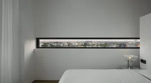 Modern minimalist bedroom featuring white walls and a city view through a horizontal window.