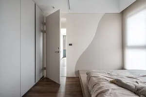 Modern minimalist bedroom featuring wooden flooring, a bed with a plush animal toy, and a minimalistic design aesthetic.