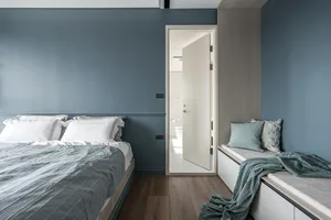 Minimalist bedroom with a bed, bench seat, and wooden floors.