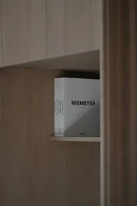 A modern minimalist bookshelf made of wood with a minimalist book titled "Niemeyer"