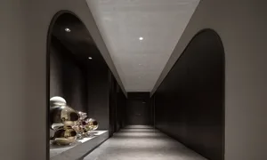 A modern minimalist corridor featuring metal spheres on a light-colored marble floor and a ceiling with recessed lighting.