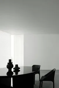 Modern minimalist dining room with glass table and black chairs, featuring a clean, uncluttered aesthetic.