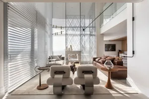A modern minimalist living room featuring a glass wall, marble fireplace, leather furniture, and wooden accents.