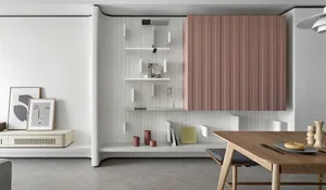 A minimalist living room with a white and pink storage unit displaying decorative items and books.
