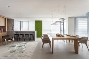 Modern residential dining room featuring wooden table, glass chairs, marble countertop, and upholstered seating.