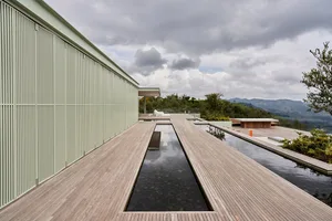 A modern architectural space featuring a wooden deck and pool with a view of the mountains.