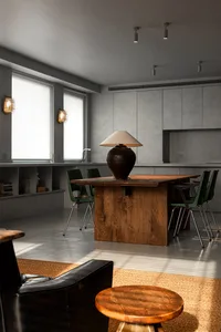 Modern kitchen interior featuring a wooden table with a lamp and green chairs.