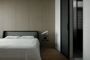 Minimalist bedroom with a wooden headboard and floor-to-ceiling wood panels.