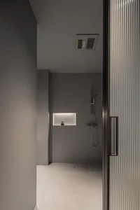 A modern minimalist bathroom with a concrete floor and walls, featuring a shower with a minimalist design.