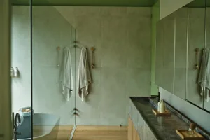 A modern bathroom featuring concrete walls, minimalistic design, and a Zen-like atmosphere with natural lighting and floor-to