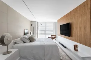 A modern bedroom with minimalist design featuring a white bed and wooden accents.