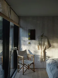A minimalist bedroom with wooden walls and a wooden folding chair.