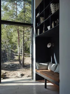A minimalist residential interior with a wooden bench, glass shelves, and metal accents.