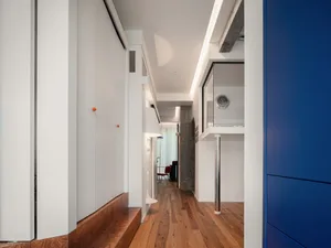 Modern interior design featuring a corridor with white concrete walls and wooden flooring.