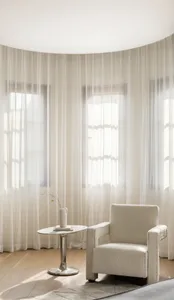 A modern living room featuring sheer curtains, wooden furniture, and a cozy atmosphere.
