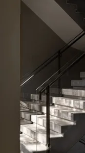 A modern marble staircase with glass railings.