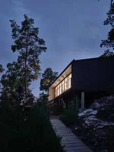 A modern minimalist house with wooden exterior and large windows at dusk.