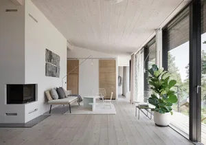A minimalist living room featuring white walls, a wooden floor, and a mix of glass and concrete furniture.