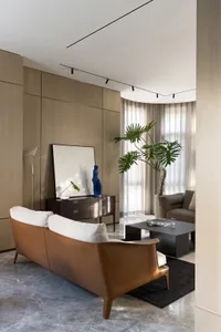 A minimalist living room with a comfortable leather sofa and a sleek coffee table, featuring large windows and modern decor.