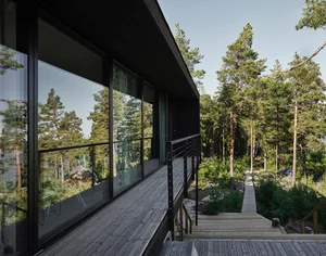 Modern residential exterior featuring bamboo deck and forest backdrop.