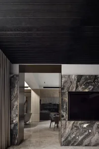Modern, minimalist kitchen area with marble countertops and dark wood accents.