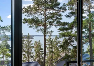 Industrial-style vacation home with large windows overlooking a serene lake surrounded by trees.