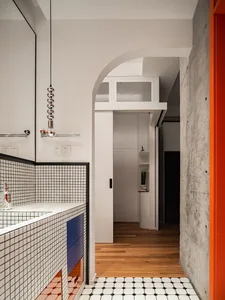 Modern bathroom with white and black tiled walls, blue drawers, and a concrete floor.