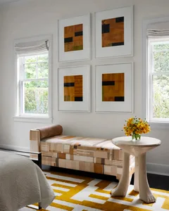 A modern bedroom featuring soft furnishings with a unique geometric pattern, complemented by a vibrant textured rug and minim
