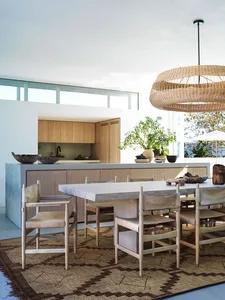 Modern kitchen featuring a concrete dining table, rattan pendant light, and wooden cabinets.