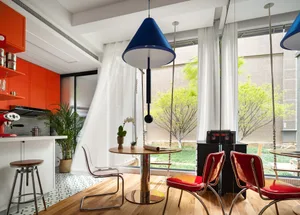 A modern kitchen with red and orange upholstered chairs