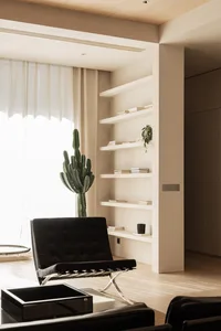 Modern living room with a bookshelf, black chair, and cactus plant.