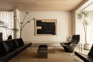 Modern living room featuring a black leather sofa, a glass coffee table, and a wooden coffee table with a geometric black and