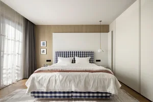 Modern minimalist bedroom with white furniture, patterned headboard, wooden flooring, and tall windows.