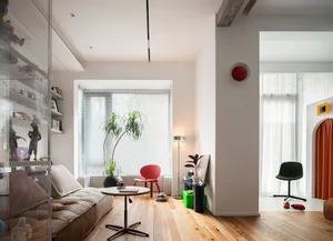 Modern minimalist living room with wood floors, glass wall, and red and green accents.