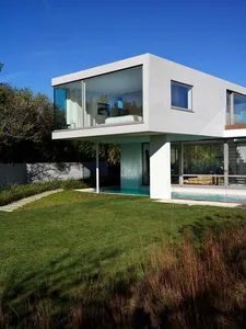 Modern residential house with a concrete exterior and a green lawn.