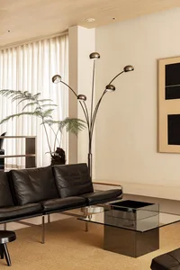 Contemporary living room featuring glass coffee table, black leather sofa, wooden coffee table, and modern floor lamp.