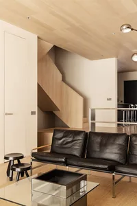 A modern living room with wood floors, walls, and furniture.