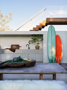 Outdoor kitchen with modern design featuring metal elements and a wooden table.