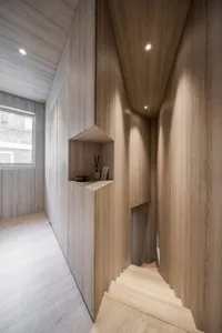 Modern wooden stairs with a minimalist design, featuring a built-in shelf and a window providing natural light.
