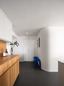 A modern kitchen with minimalist design, wooden cabinets, marble countertops, and a blue bench.