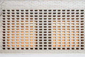 A white brick wall featuring a geometric pattern with alternating solid and transparent bricks.