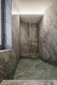 Modern bathroom with marble walls and floor, featuring a walk-in shower and sleek design.