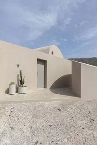 A minimalist concrete home exterior with a small cactus plant in a white planter.
