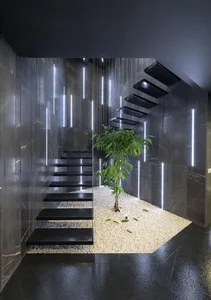 A modern floating staircase with black metal steps and a central potted plant.