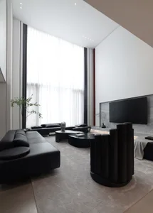Modern living room with black and white decor, featuring a metal and leather sofa, minimalist coffee table, and large windows