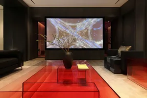 Modern living room featuring a glass table with a red tablecloth, a large screen displaying a complex network of roads, and b